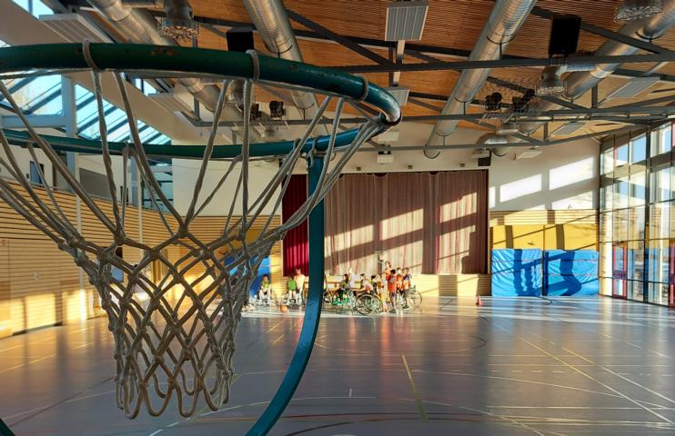 Basketballkorb im Hintergrund Schulklasse beim Rollstuhlbasketball