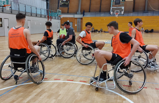 Trainer Werner Rieger erklärt Jugendlichen die richtige Aufstellung in der Verteidigung beim Rollstuhlbasketball.